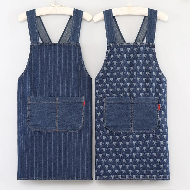 A pair of navy blue striped denim cross-back aprons displayed on a hanger.