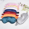 A collection of silk sleep masks in various pastel and deep colors laid out on a white surface.