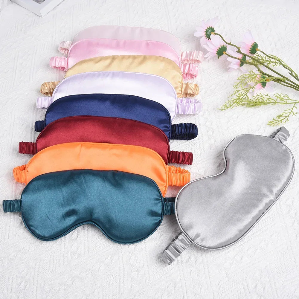 A collection of silk sleep masks in various pastel and deep colors laid out on a white surface.