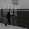 A modern kitchen countertop with a black slab and dark cabinetry, featuring a marble peel-and-stick backsplash film above.
