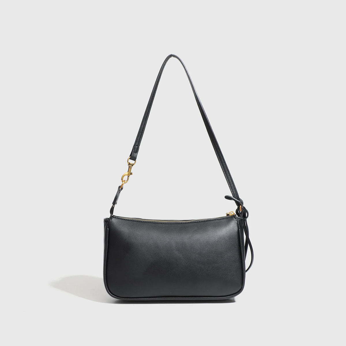 A black classic leather tote bag with a long strap and a gold-toned metal buckle.