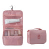 A pink travel makeup bag with a hanging hook, showing organized cosmetic and toiletry storage.