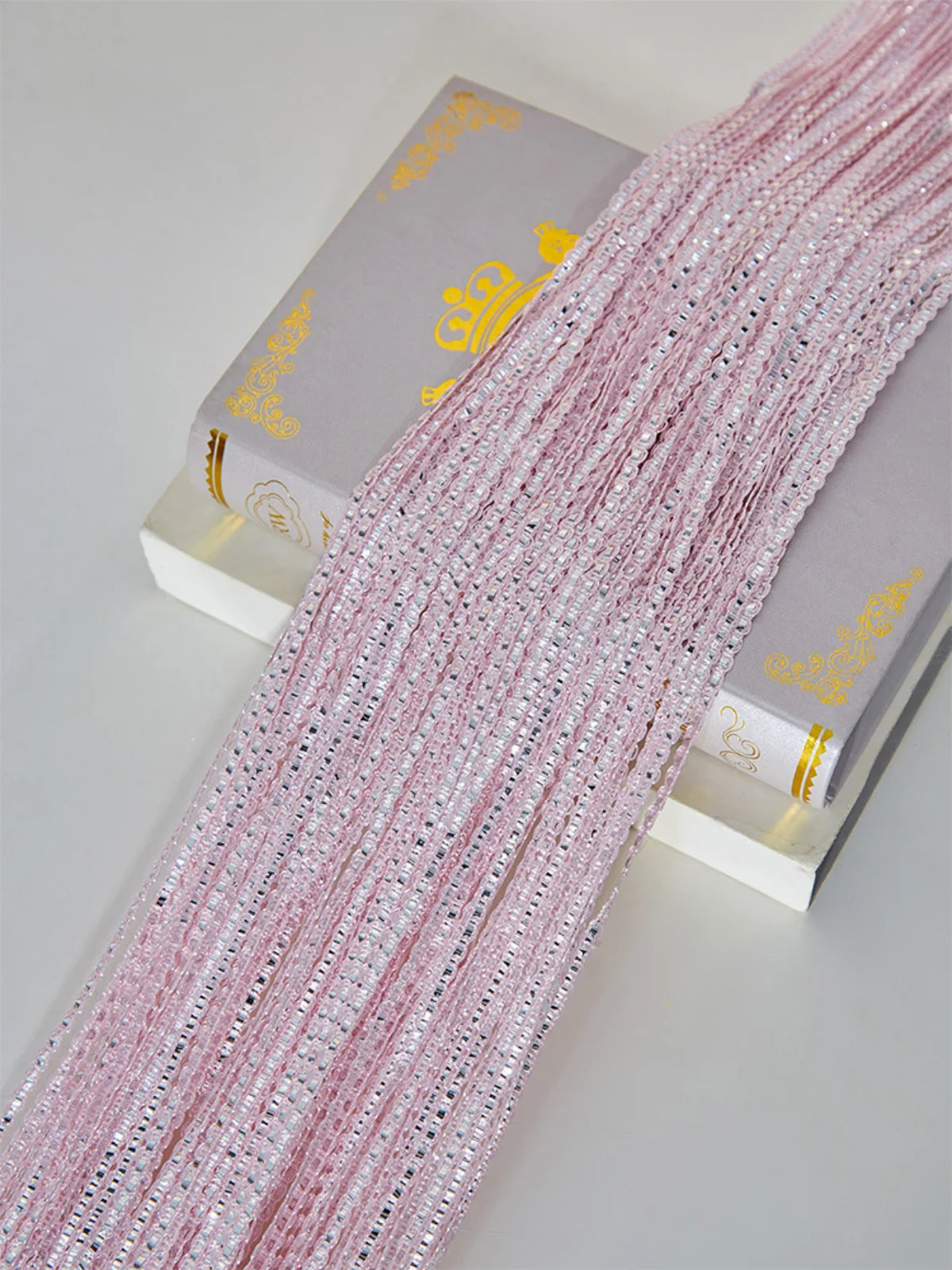 Pink glitter tassel string curtain for doorways and room dividers displayed next to its packaging.