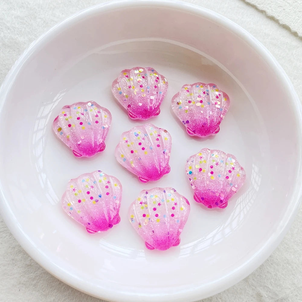 Pink iridescent seashell resin charms scattered in a white bowl