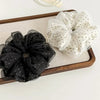 A pair of black polka dot mesh scrunchie hair ties and a white polka dot fabric scrunchie displayed on a wooden tray.