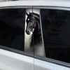A close-up view through a car window showing a black horse head decal on the glass.