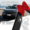 Red rhinestone bow decorations installed on a car license plate frame.