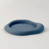 A round, matte blue silicone coaster with a slightly raised rim is shown on a white surface.
