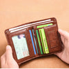 A hand holds a brown PU leather card holder wallet filled with various cards and a credit card.