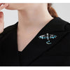 A close-up of a black blazer lapel featuring an enamel dragon brooch with iridescent accents.
