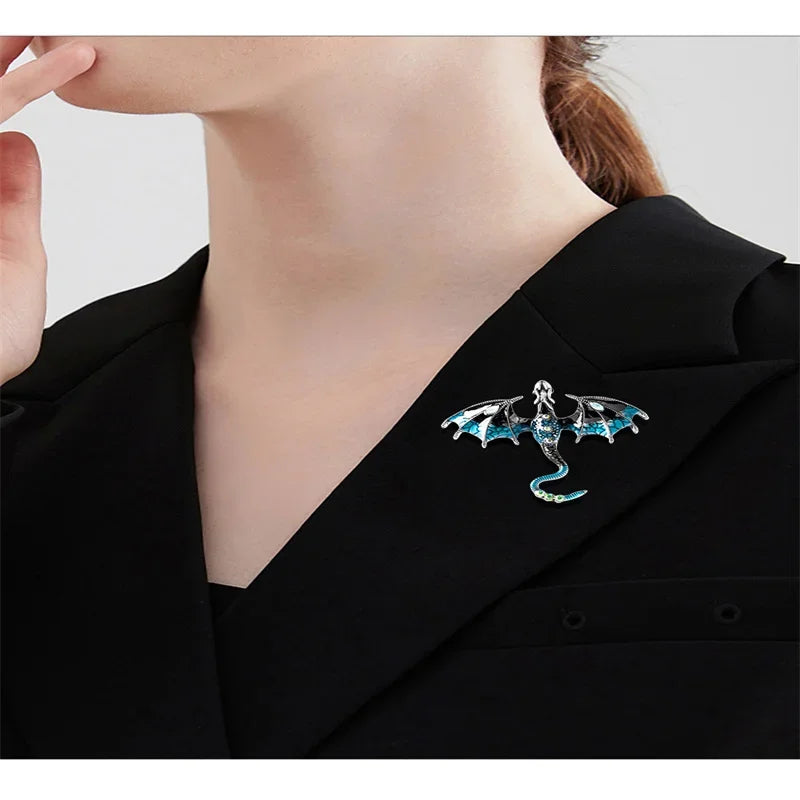 A close-up of a black blazer lapel featuring an enamel dragon brooch with iridescent accents.