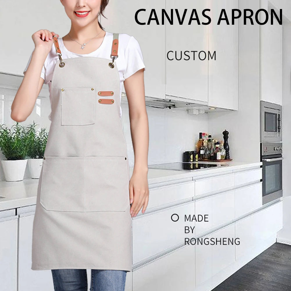 A woman wearing a light beige canvas apron with large front pockets in a kitchen setting.