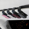 A close-up view of a black crystal rhinestone car sun visor sunglasses clip mounted on a white surface.