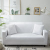 A white silky soft stretchable sofa cover displayed on a modern couch with decorative framed art above.