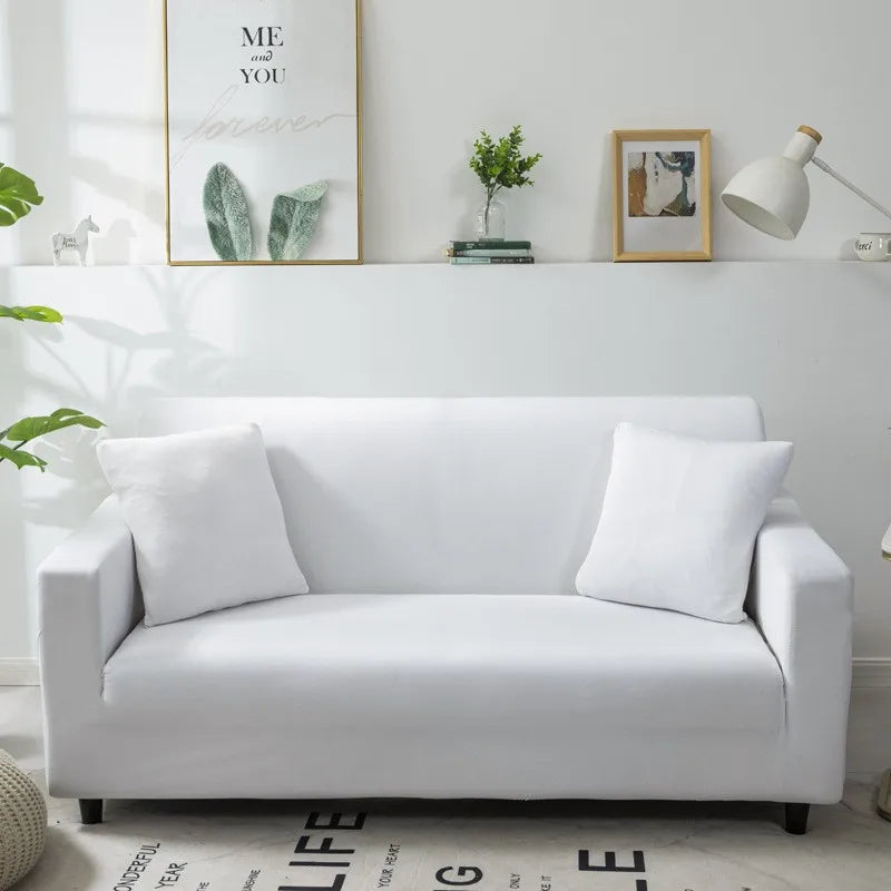 A white silky soft stretchable sofa cover displayed on a modern couch with decorative framed art above.
