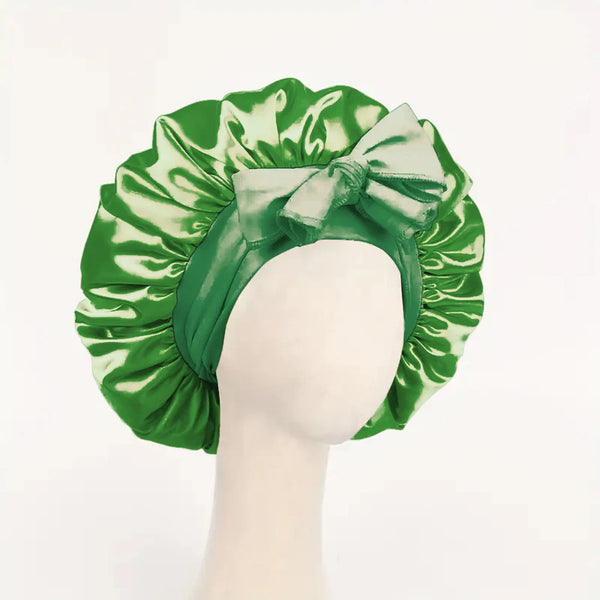 A green satin sleep bonnet tied in a bow, shown on a mannequin.