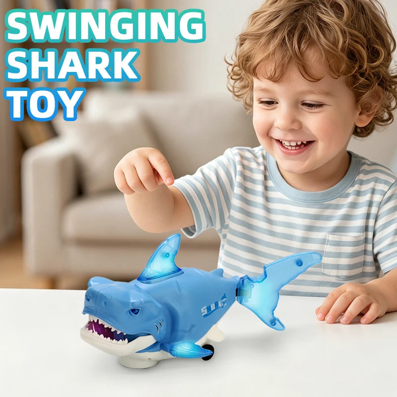 A smiling toddler is playing with a blue plastic swinging shark toy on a white table.