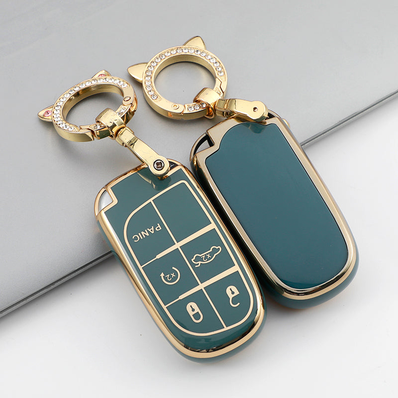 A gold-toned key fob with a green TPU case cover and a ring attached, shown against a gray background.