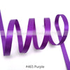 Purple satin ribbon looped and draped against a white background