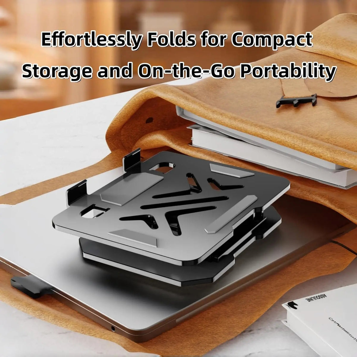 A compact carbon steel tablet stand is shown folded on a leather surface next to a laptop.