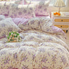 A floral duvet cover set featuring lavender and white patterns on a bed with matching pillows and a bedside table.