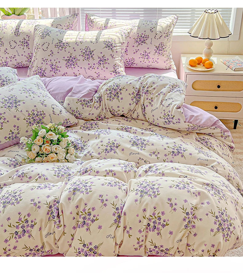 A floral duvet cover set featuring lavender and white patterns on a bed with matching pillows and a bedside table.