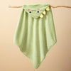 A light green hooded baby bathrobe towel with a cartoon dragon face design hanging on a wooden branch.
