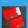 Two red RFID blocking card sleeves are shown on a dark surface next to a white identification card.