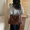 A woman is holding a brown leopard print duffle bag with an adjustable strap in a hallway.