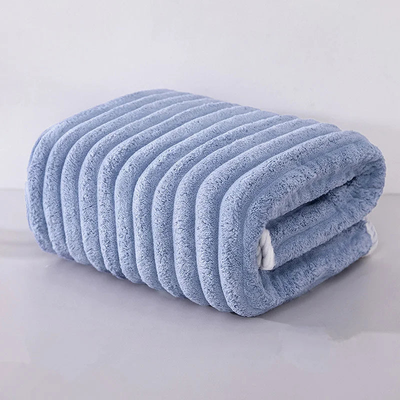 A rolled light blue microfiber towel with ribbed texture is shown on a white surface.
