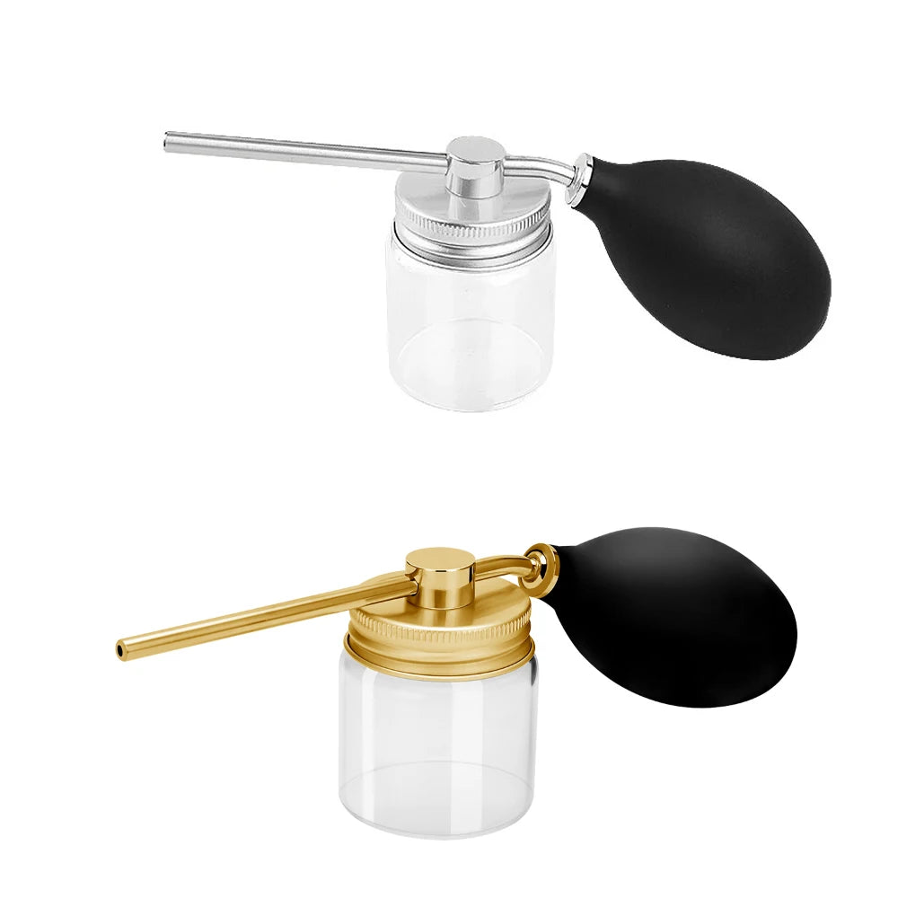 A refillable hair fiber powder spray bottle with a silver metal applicator and a black rubber bulb top.