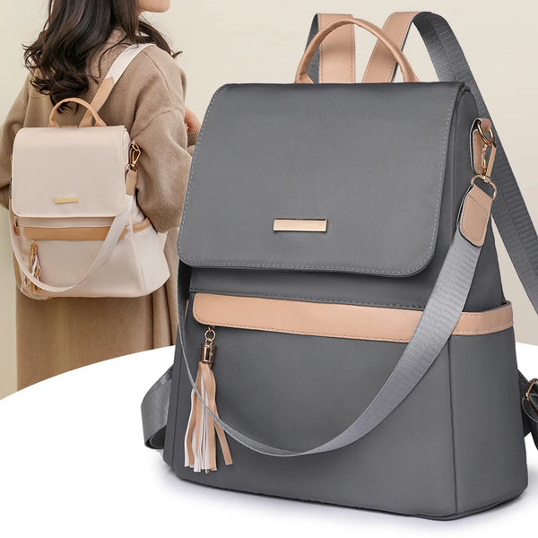 Una mochila gris minimalista antirrobo con detalles y correas color arena junto a una persona.