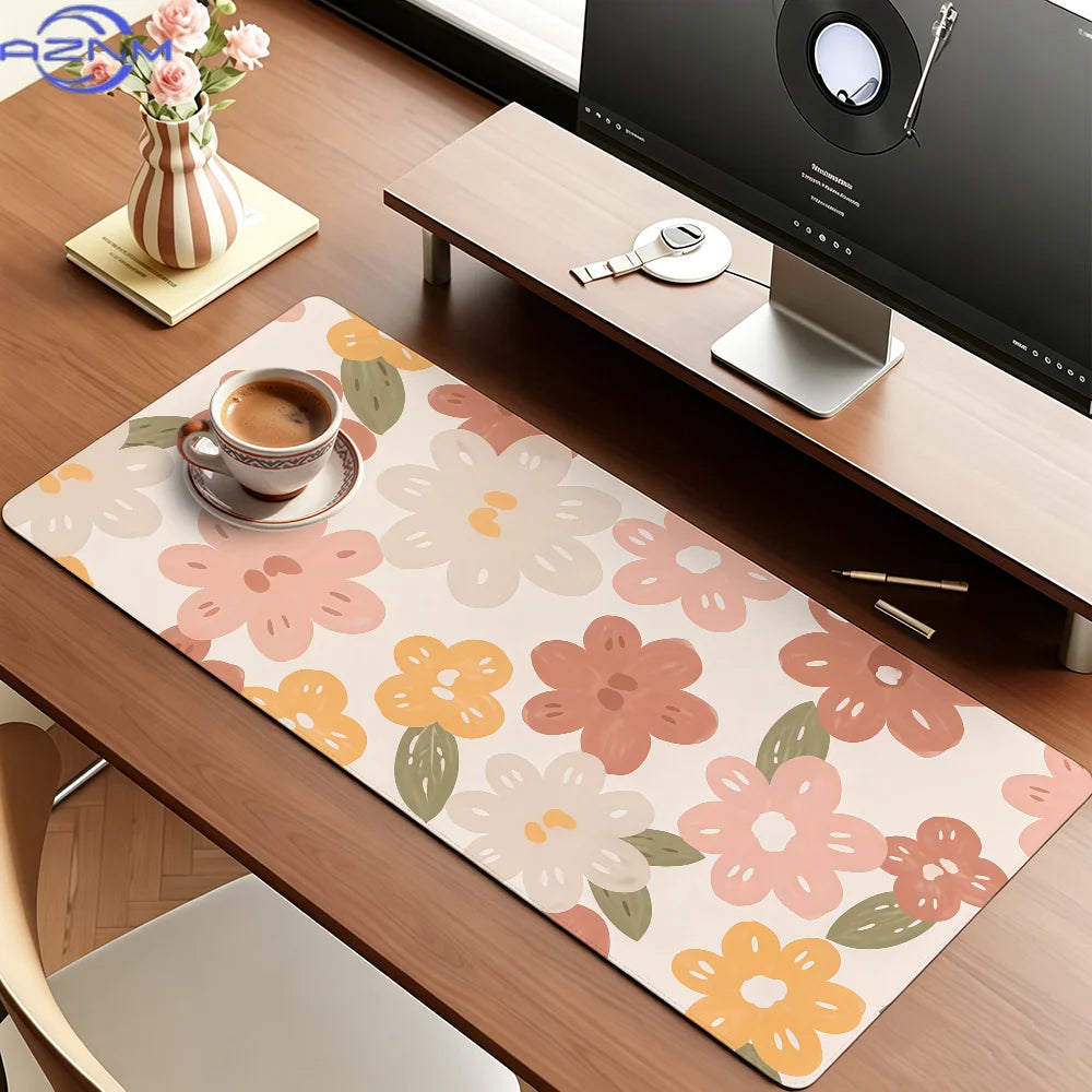 A pink floral mouse pad with various flower shapes rests on a wooden desk next to a laptop.