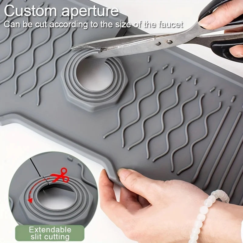A hand uses scissors to cut a custom aperture in a gray silicone faucet splash guard, demonstrating extendable slit cutting.