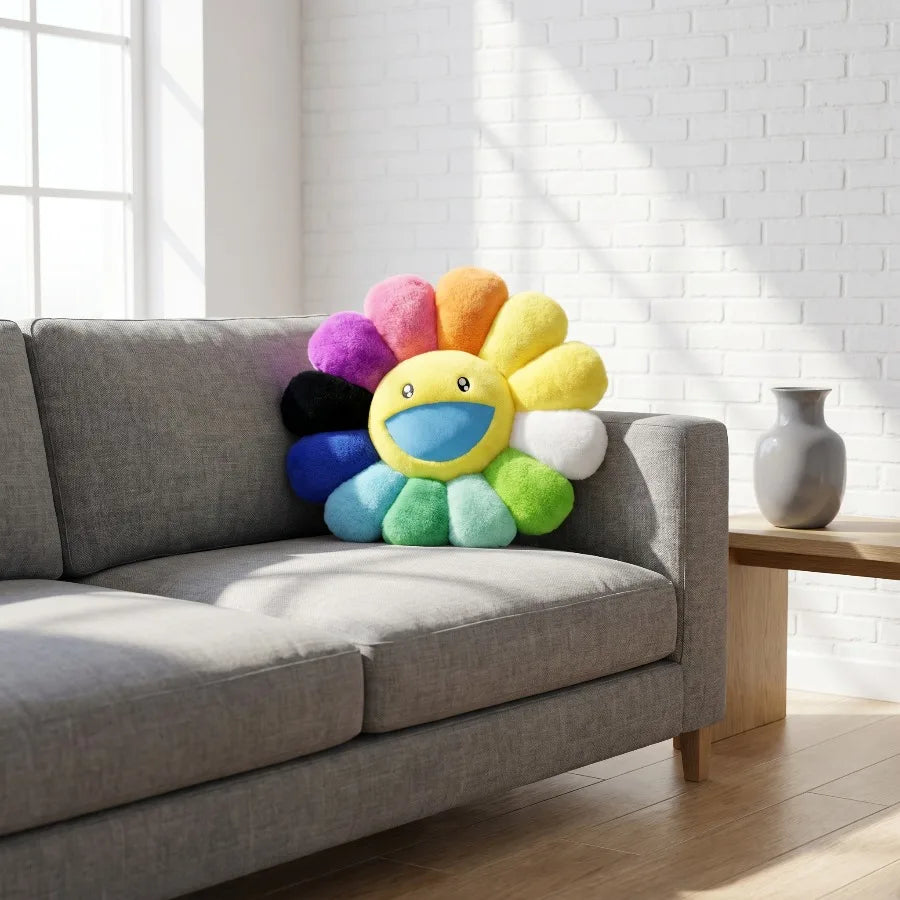 A cheerful sunflower plush cushion with a smiling face in various bright colors sits on a gray sofa.