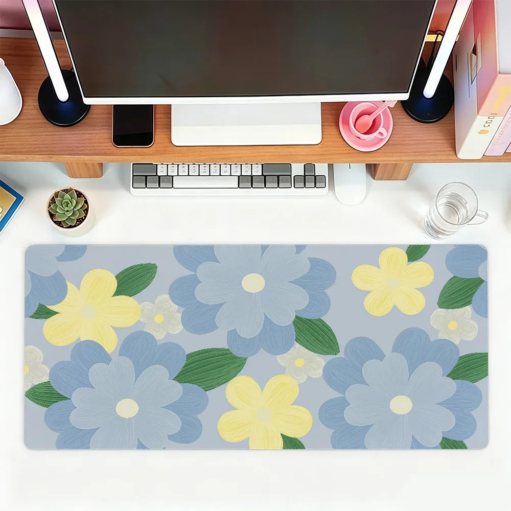 A light blue floral mouse pad featuring yellow and white flowers placed on a wooden desk with a computer setup.