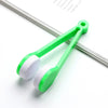 A bright green portable double-sided glasses cleaning brush with white microfiber pads resting on a white surface.