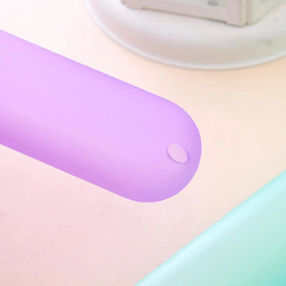 A purple portable toothbrush travel case with a smooth, elongated design is shown on a light pink surface.