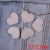 A set of five pink glitter heart iron-on embroidered patches placed on a denim fabric.