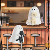 A blind box featuring two ghost-like figurines, one white and one dark gray, displayed in a cafe setting.