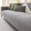 A gray chenille sofa cover with olive green pillows on a light-colored sofa.