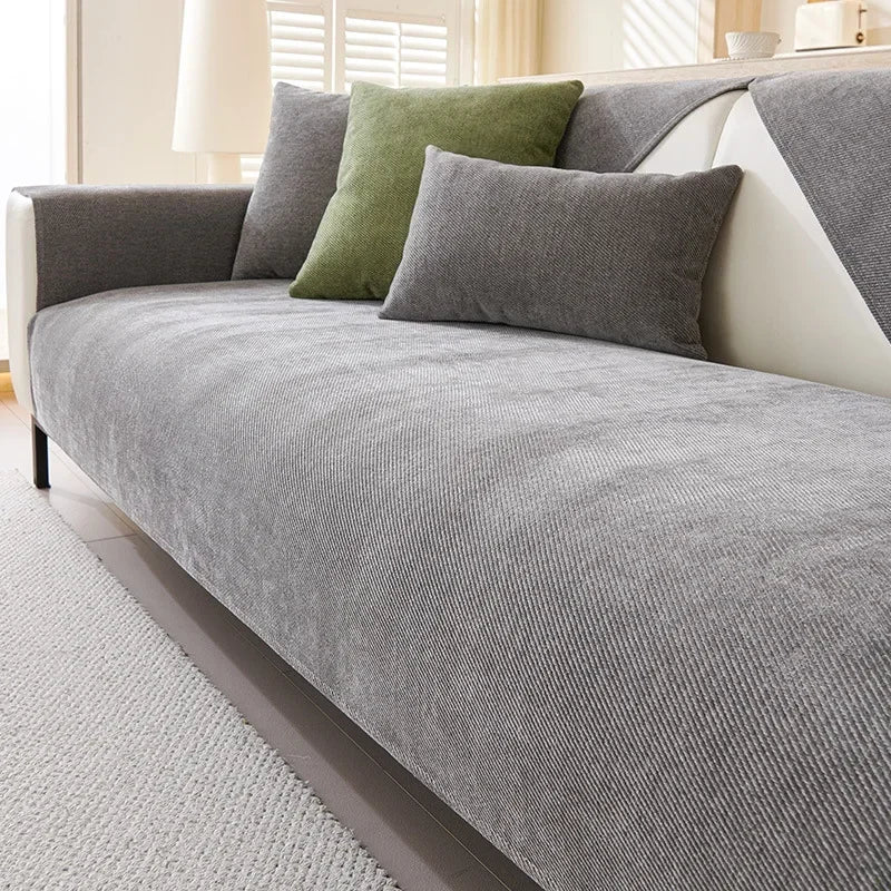 A gray chenille sofa cover with olive green pillows on a light-colored sofa.
