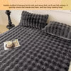 A dark gray quilted blanket and pillow featuring a textured, fluffy surface.