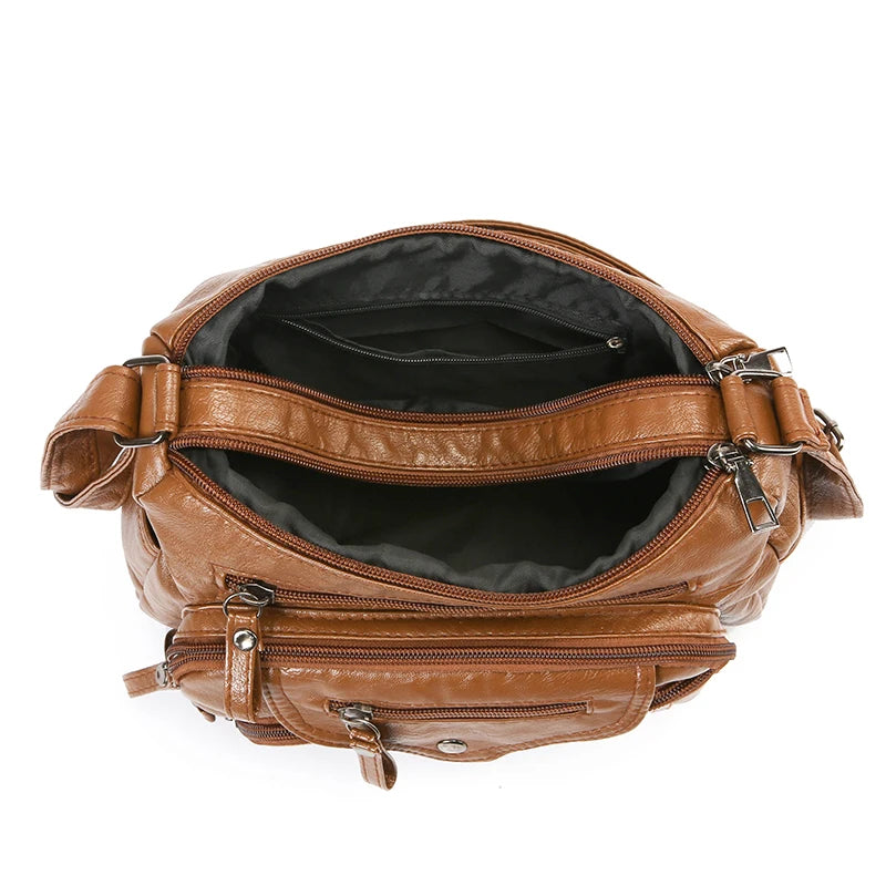A brown leather tote bag with a dark lining and adjustable strap, shown open.