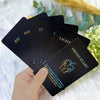 A hand holds a deck of oracle cards with titles like Recognition, Light, and Fresh Start against a blurred green background.