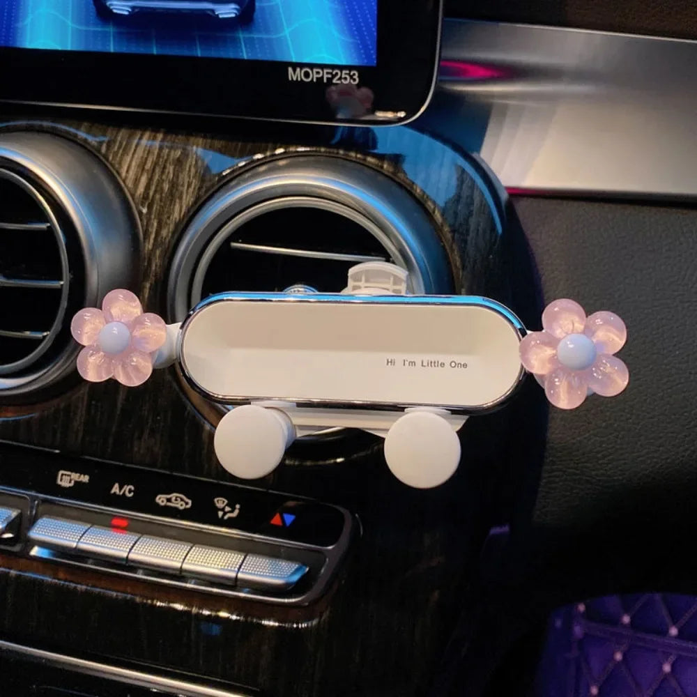 A white gravity car phone mount is shown installed in a car air vent.