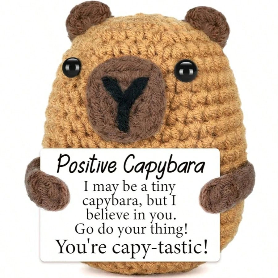 A handcrafted crochet bear figurine with an inspirational card featuring a positive message.
