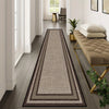 A long runner rug with geometric patterns in shades of brown, grey, and beige placed on a wooden floor.