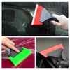 A hand is using a red and black car window squeegee to clean a car window.