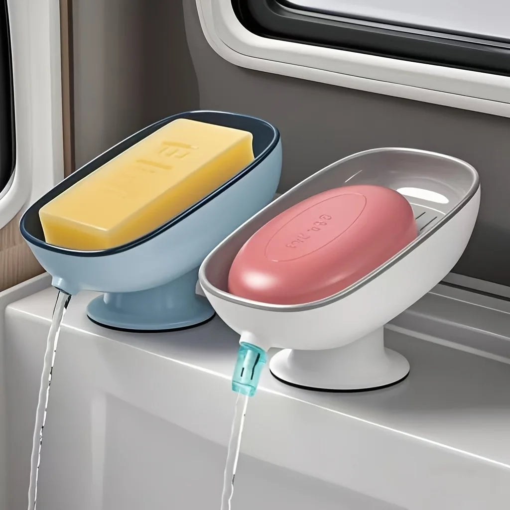 A light blue soap dish with a yellow bar of soap is draining water into a tray in a window sill.
